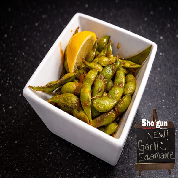 A white bowl of garlic edamame with a lemon wedge, from Shogun Japanese restaurant.