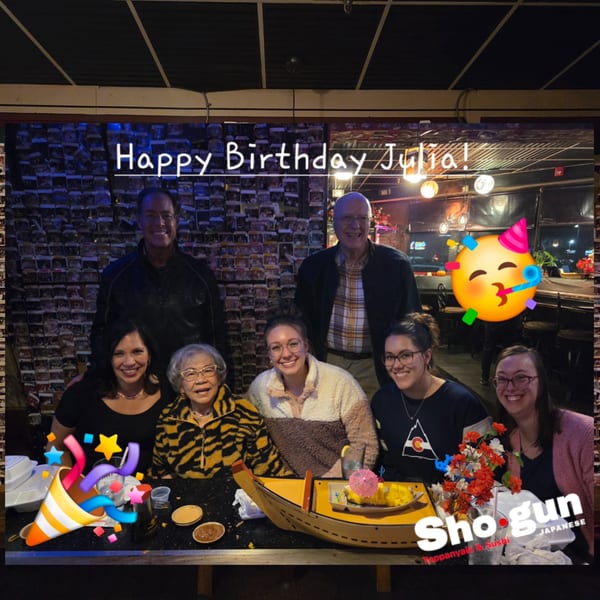A group of seven people celebrating a birthday at a hibachi table at Shogun Japanese Steakhouse.