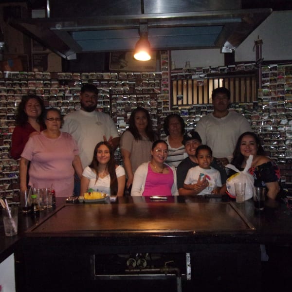 A large family group poses happily around a hibachi grill table at Shogun Japanese Steakhouse.