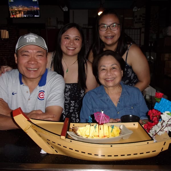 Four smiling people pose with a pineapple dessert served in a decorative boat at Shogun Japanese Steakhouse.
