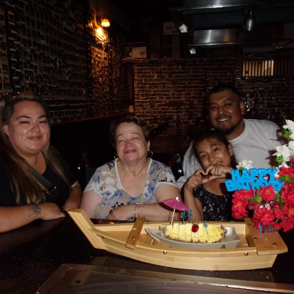 Four people celebrating a birthday at Shogun Japanese Steakhouse with a pineapple dessert boat.